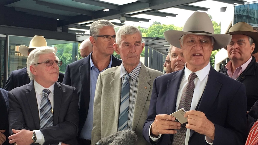 Bob Katter standing in front of a group of older white men in suits.