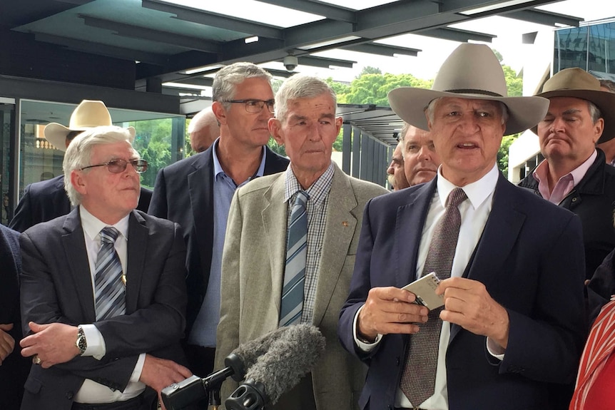 Bob Katter standing in front of a group of older white men in suits.