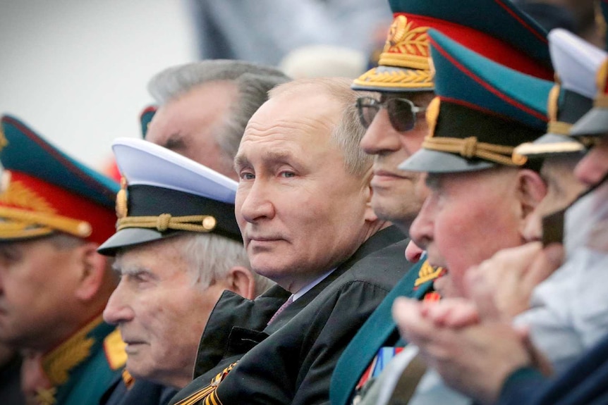 Президент России Владимир Путин стоит в очереди с другими официальными лицами.