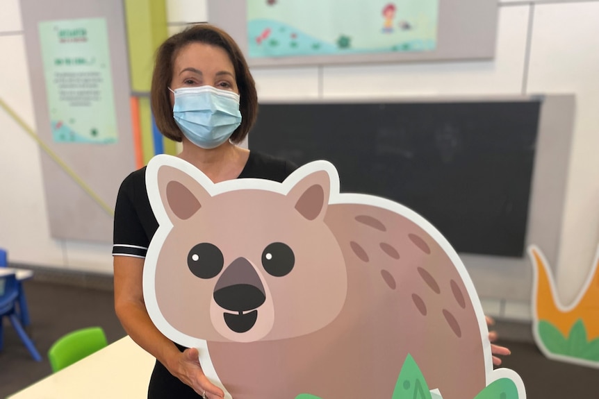 A woman holding a cardboard wombat