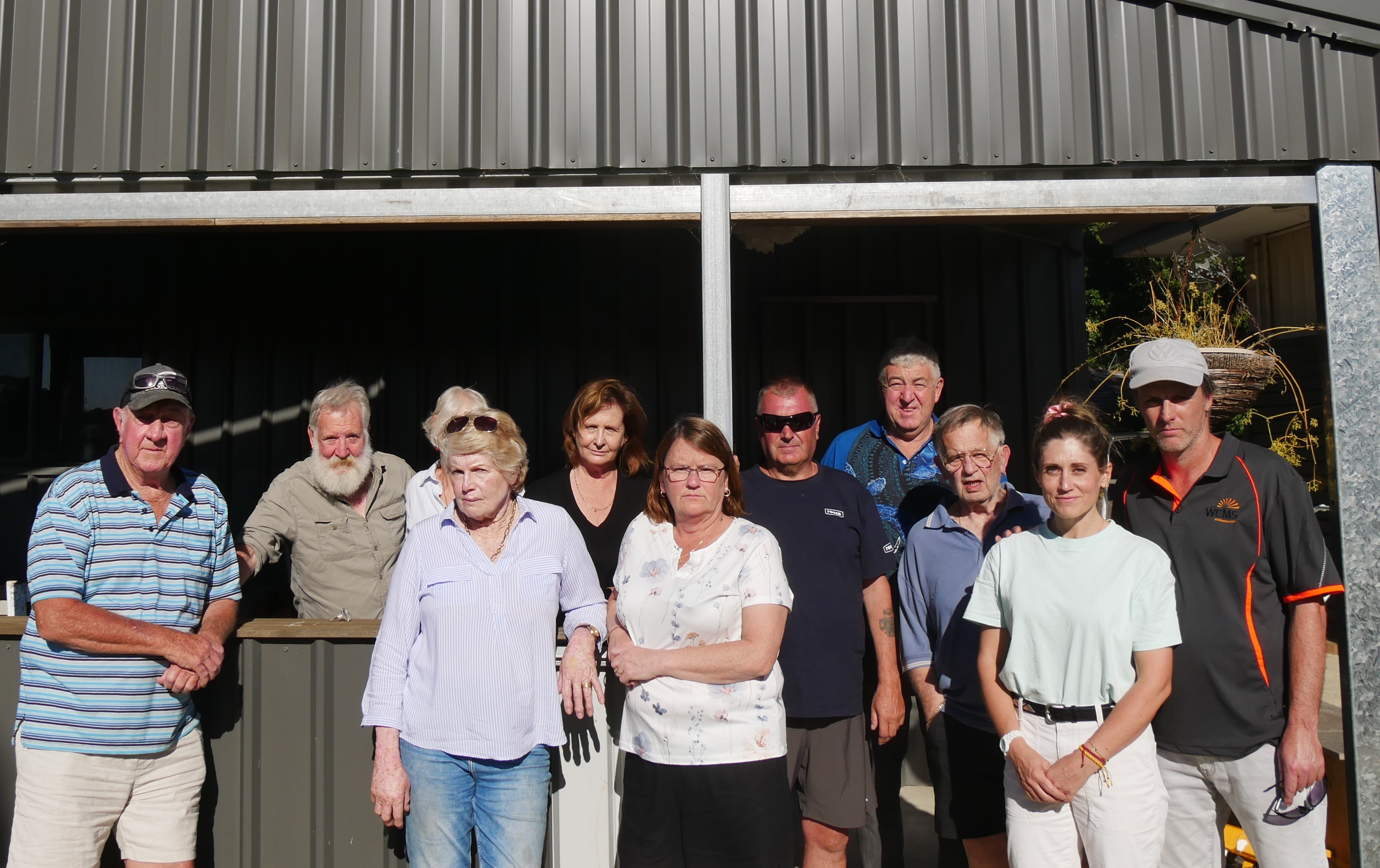 Un grupo de personas se encuentran juntas frente a un cobertizo.