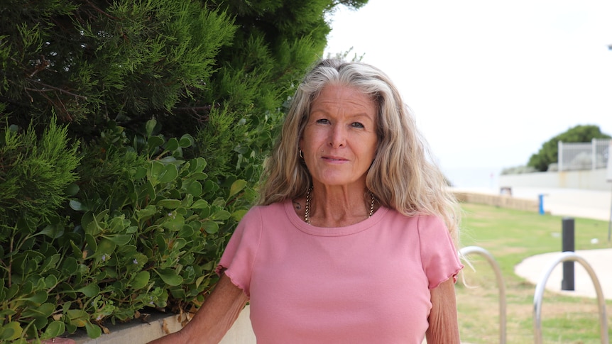 A woman in a pink top standing in a park
