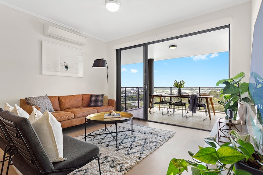 Inside a completed apartment looking at living room and verandah with furniture.