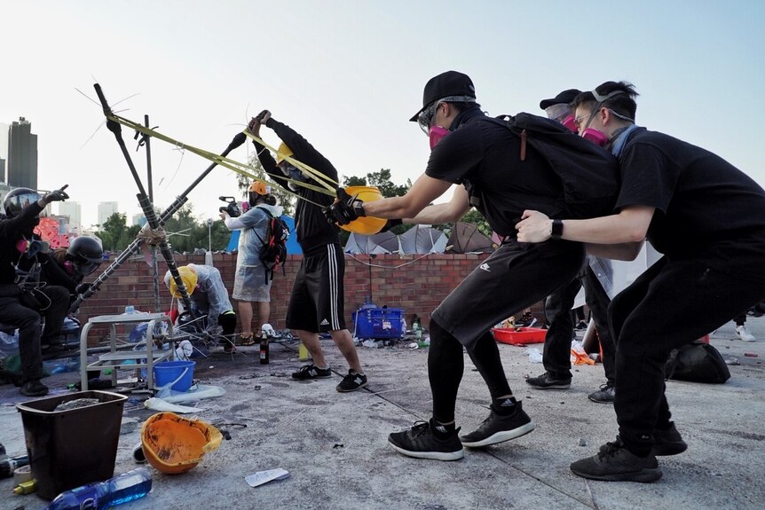 Students using a construction worker's helmet to fire rocks from a catapult