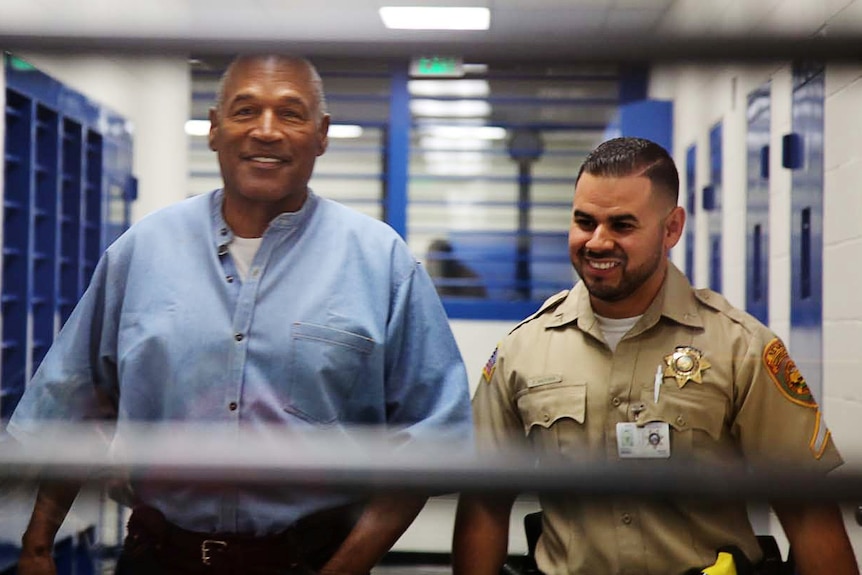 OJ Simpson (L) arrives for his parole hearing wearing a blue shirt with a white t-shirt underneath.