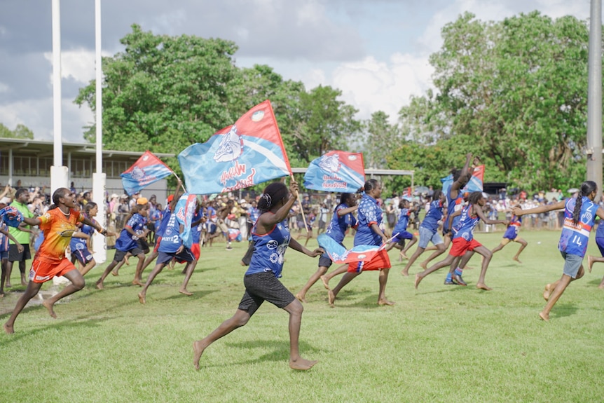 Scores of fans storm across the field at Tiwi Islands football grand final.