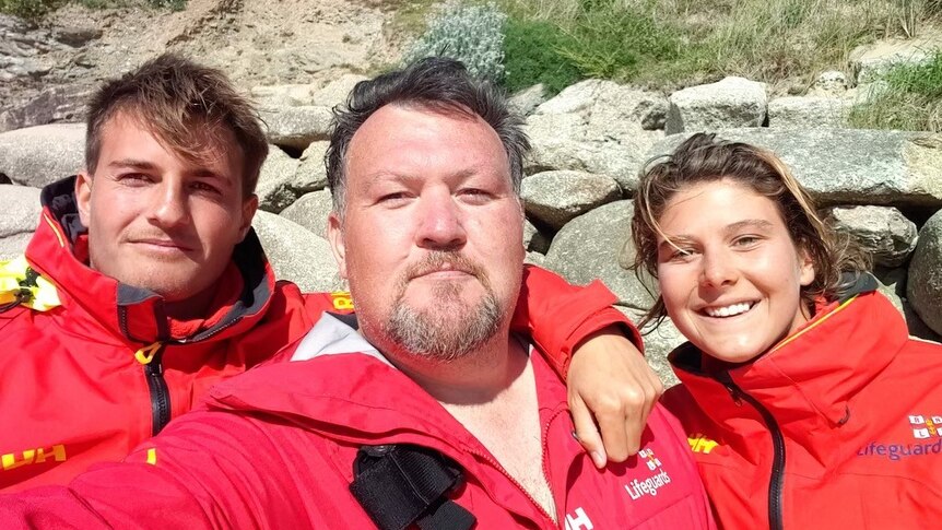 John (middle) with his life guards Alex and Tori who rescued him from the surf in Cornwall.