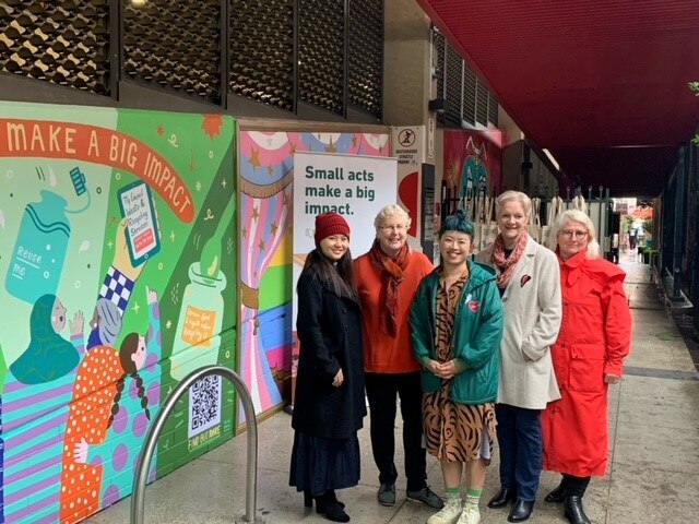 a group of people stand next to a mural