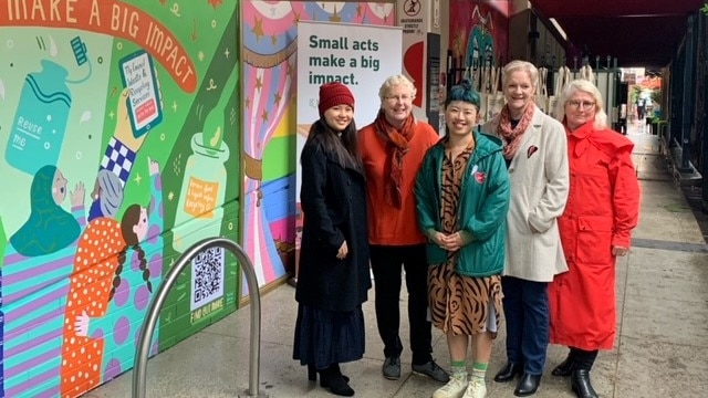 a group of people stand next to a mural