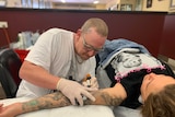 Southport tattooist Ben Bramiff at work tattooing a woman's arm