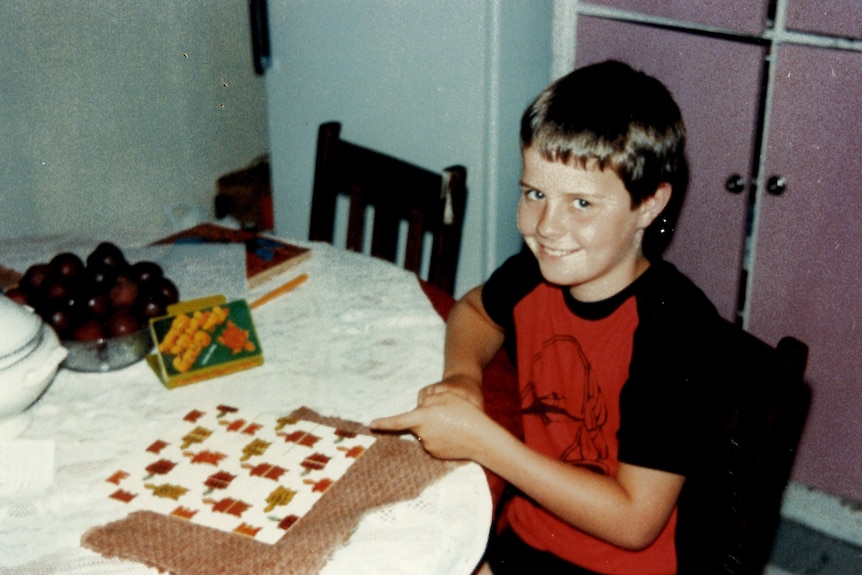 A photo of a smiling boy with a puzzle on a table.