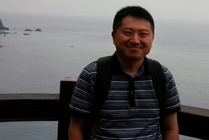 Chinese journalist Liu Hu smiles in a photo on the coat wearing a striped shirt