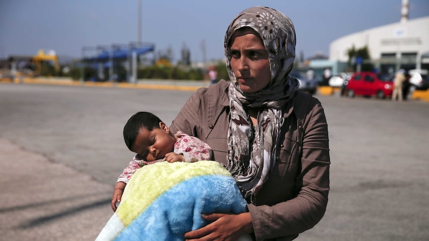 Syrian refugee holds her baby after their arrival at the port of Piraeus, near Athens