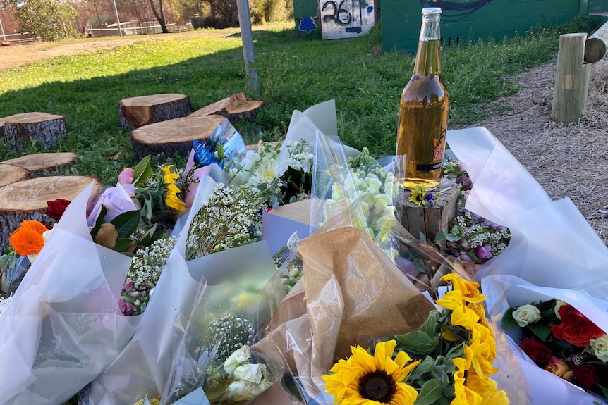 Several bouquets of flowers and a bottle of beer.