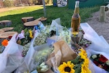 Several bouquets of flowers and a bottle of beer.