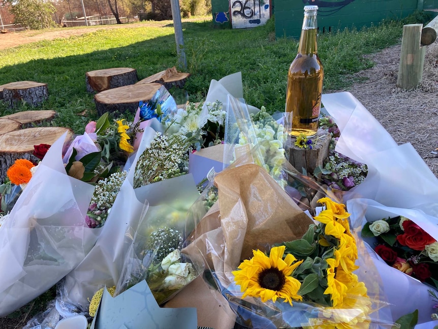 Several bouquets of flowers and a bottle of beer.