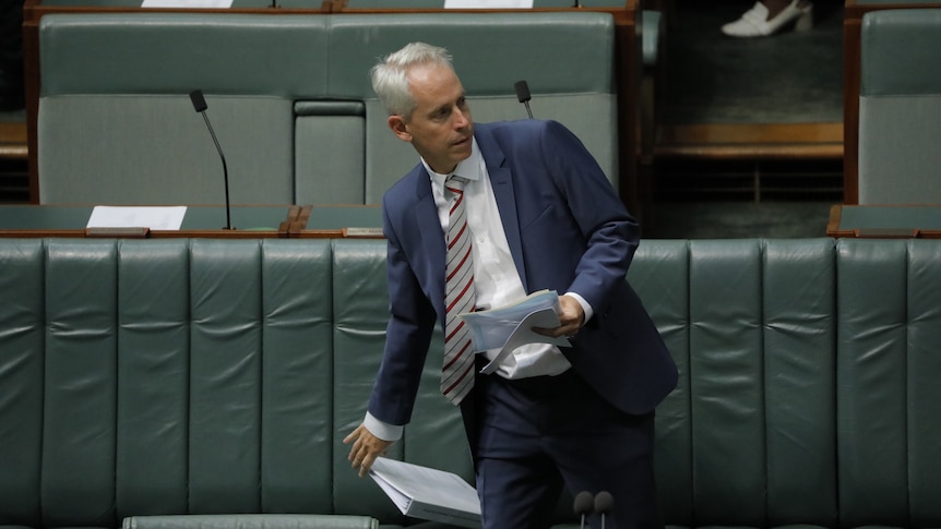 Andrew Giles holds legislation while standing up in the House of Representatives