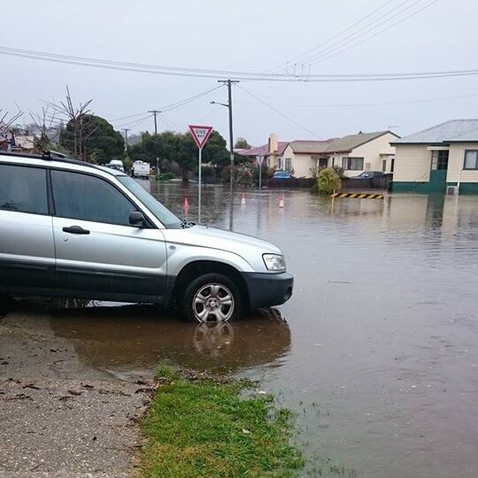 A silver four-wheel-drive is facing a flooded street.