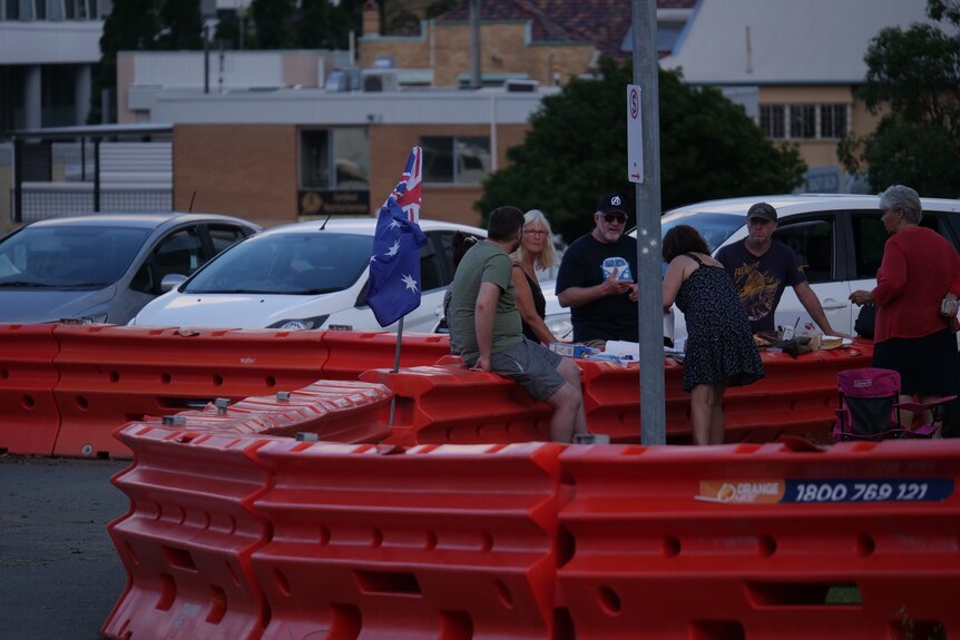 Friends meet and sit on the old, orange, barricades at the Coolangatta border.