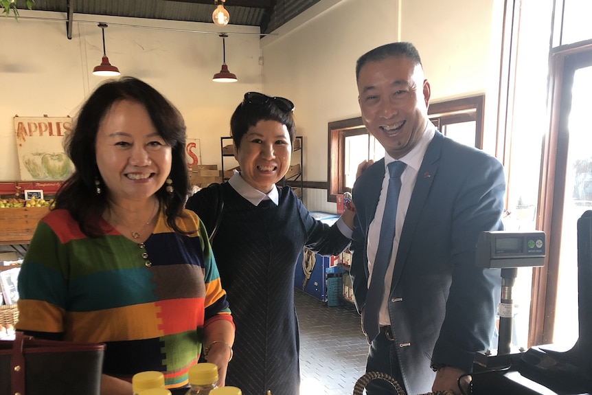 Two women and a man standing in front a cash register