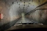 A view through the windscreen of a ute shows a tunnel sloping down.