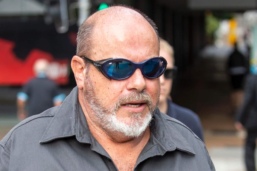 Queensland Rail worker Andre-Shane Moorby wearing sunglass walks down the street.