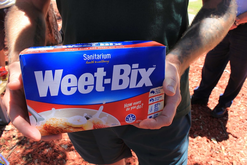 Close up image of inmates hands holding a donated box of cereal.