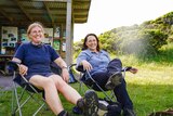 Two woman sit back on camp chairs side by side.