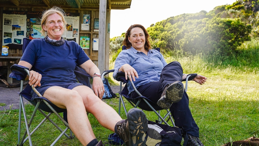 Two woman sit back on camp chairs side by side.