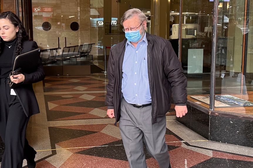 A man leaves court wearing a mask