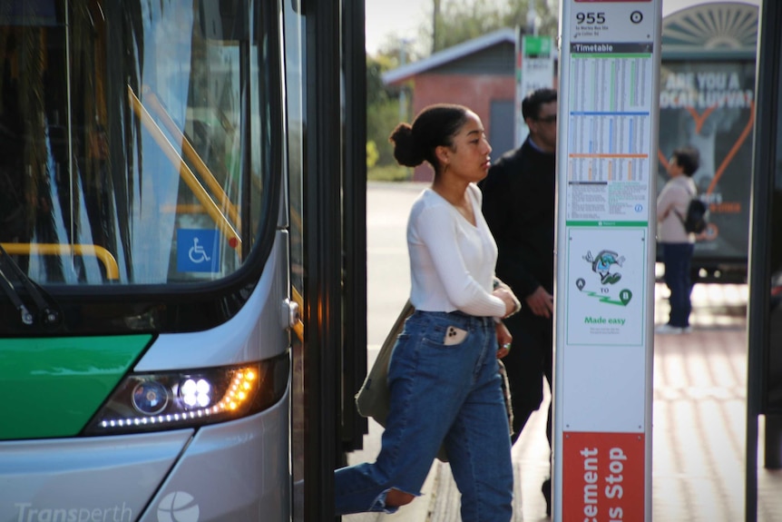 A side-profile of a young woman stepping off a bus
