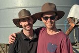Two smiling men with moustaches, wearing broad-brimmed hats, with their arms around each other.