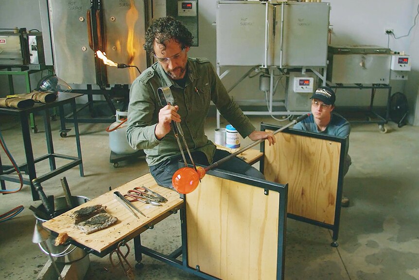 Tasmanian glass artist Keith Dougall and assistant working with glass.