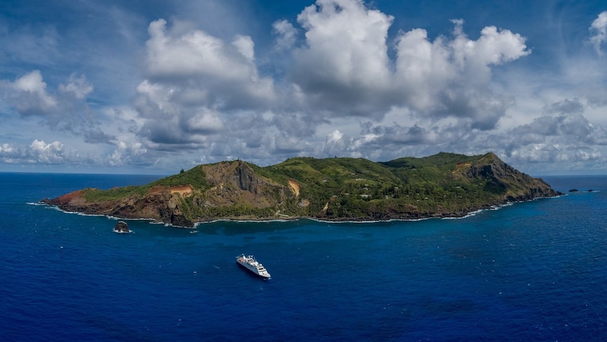 An overhead shot of Pitcairn Island with a shop anchored nearby. 