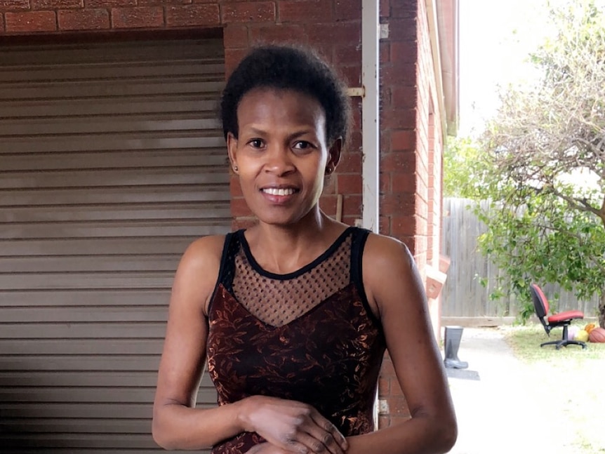 A woman in a dress standing at the front of a house.