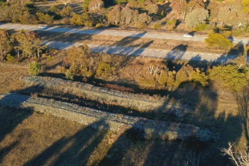 An aerial view of two long piles of glass next to the Federal Highway.