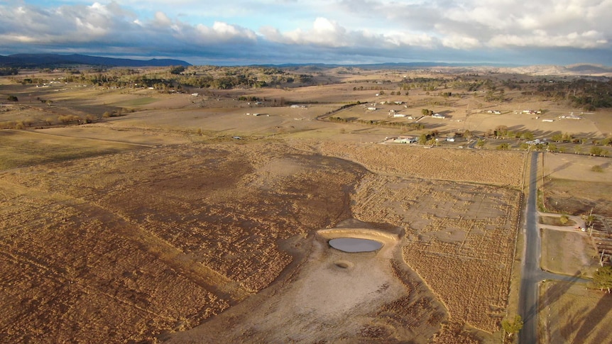 Ariel photo of dry farmland, relatively flat with hills in background