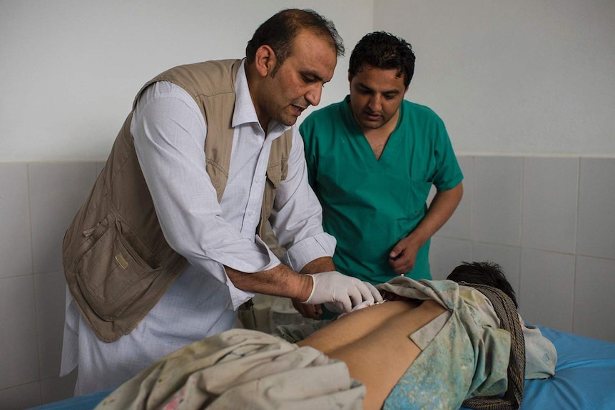Two Afghan doctors tend to a man who lost both of his legs.