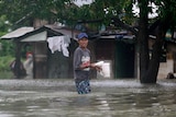 A resident carries food as he returns to his submerged house