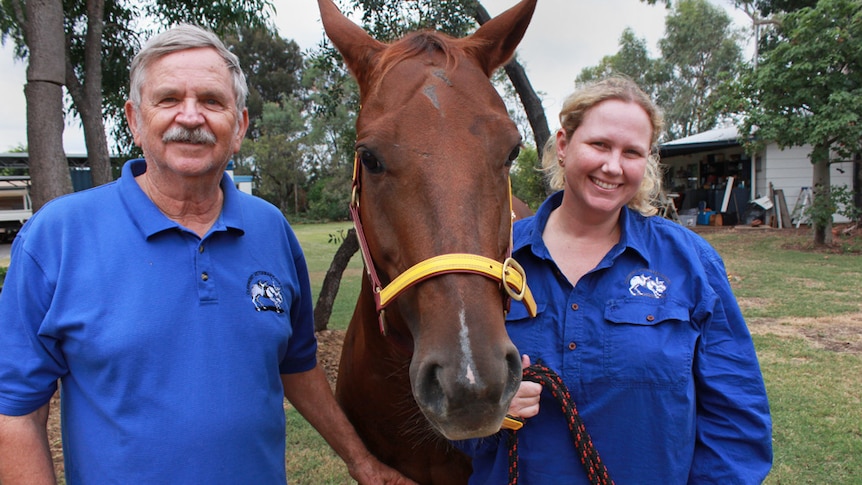 Alan and Tess stand on either side of a horse