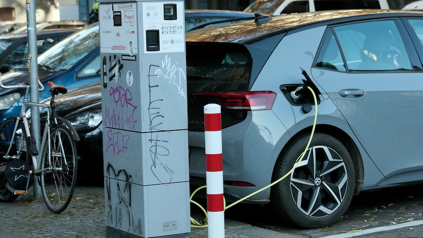 An electric VW car charges at a public charging station in Berlin