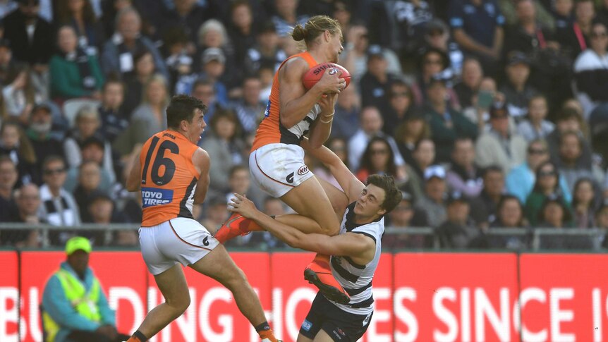 An AFL player leaps highest to take a mark ahead of an opponent