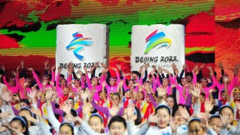 People perform in colourful outfits in front of Beijing 2022 banners.