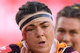 A Brisbane Broncos NRLW player attempts to palm a St George Illawarra opponent while holding the ball with her left hand.