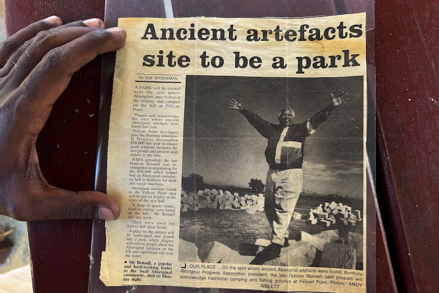 A yellowing newspaper clipping titled 'Ancient artefacts site to be a park', with an indigenous man smiling with his arms wide 