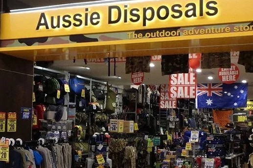 The exterior of an Aussie Disposals store in a mall showing clothing for sale.