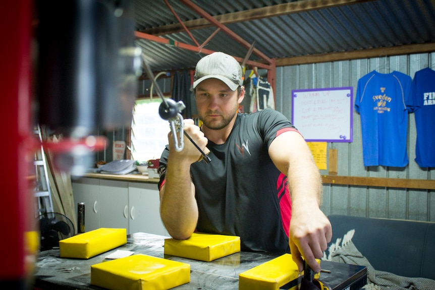 Arm wrestler Toby Whately training with a cable in a gym.