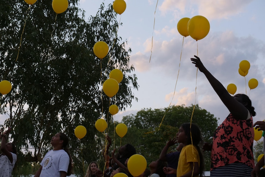 people release yellow balloons into the air