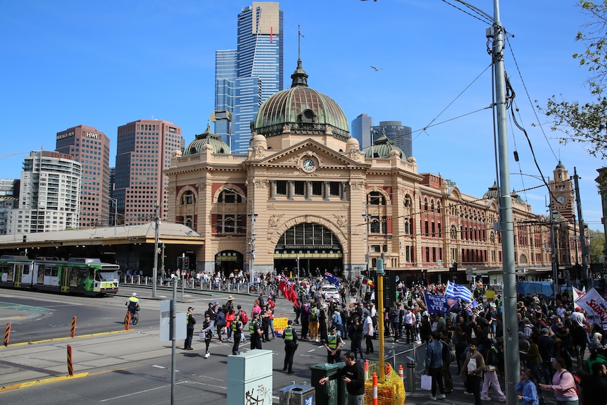 A crowd of people with australian flags and a sign thats reads 'NO to racism'