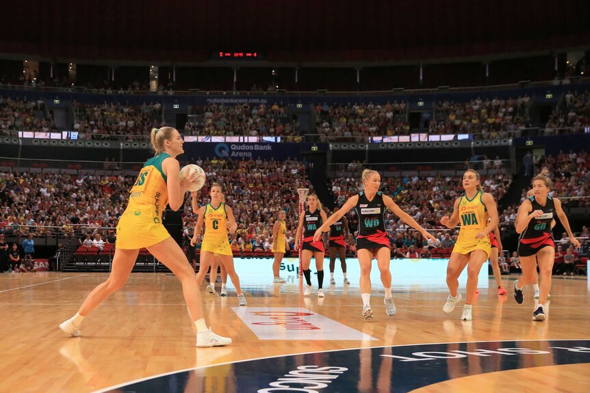 An Australian netballer shapes to pass the ball as she stands outside the two-point shot line.